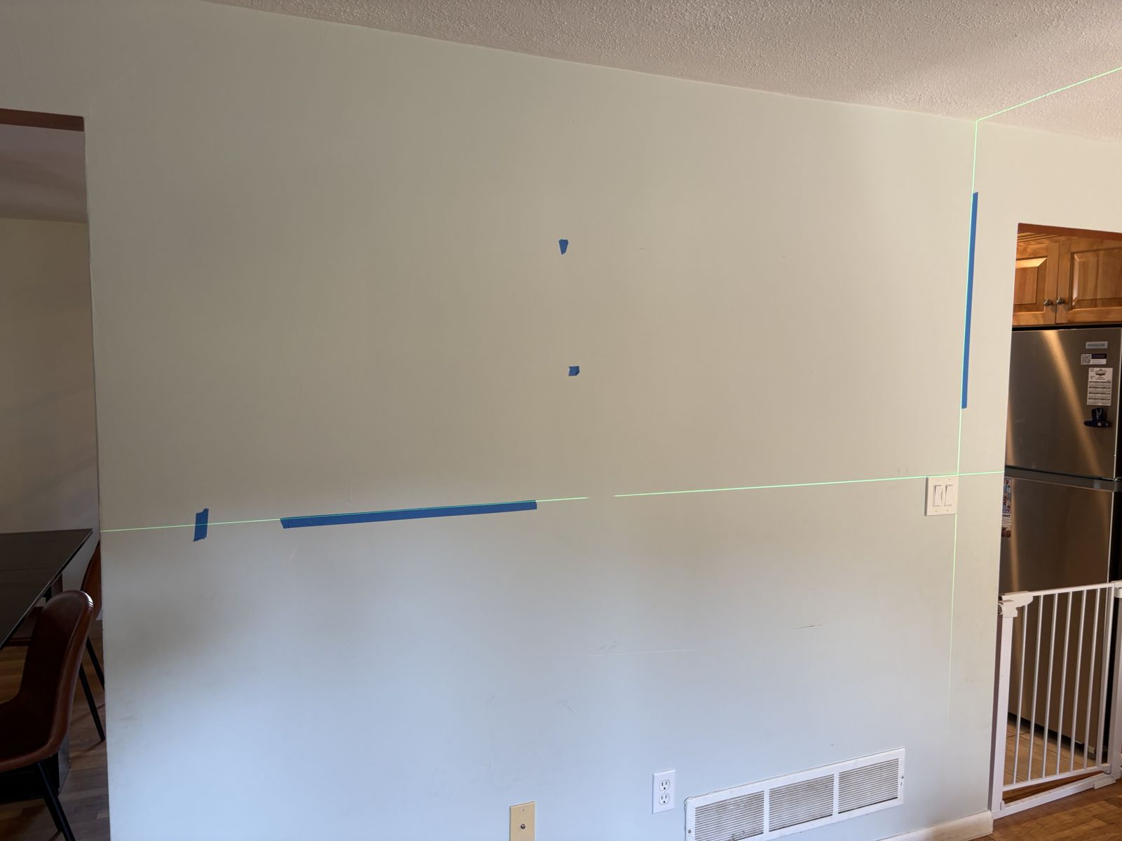 Blank wall with laser level lines and painter's tape marking shelf positions